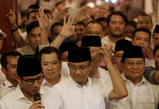 Jakarta Governor-elect Anies Baswedan holds the hand of Gerindra party chairman Prabowo Subianto as his running mate Sandiaga Uno talks to reporters after the vote on Wednesday (19/04). (Reuters Photo/Beawiharta)