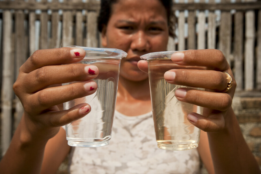 A woman holds a glass of purchased water, left, and a glass of water from an underground well in Kamal Muara, North Jakarta, where the ground water is unfit for consumption. (JG Photo/Yudha Baskoro)
