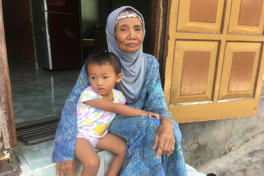 Surayah sits outside her home with her granddaughter in Singaraja, northern Bali, on June 8. (Reuters Photo/Michael Taylor)