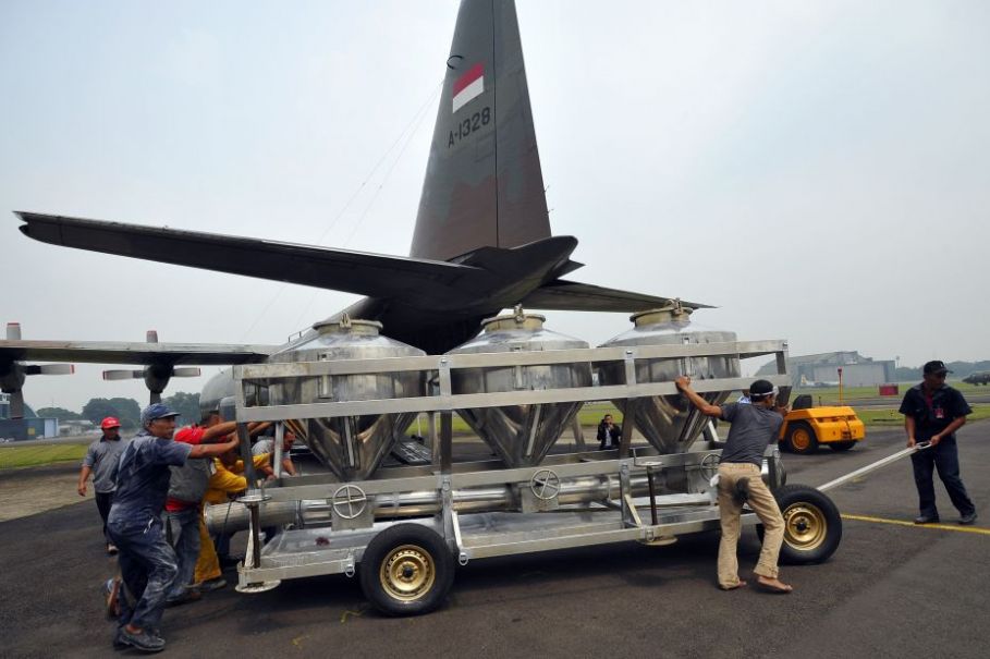 Sejumlah petugas membawa tangki berisi garam untuk dinaikkan ke pesawat Hercules C-130 di Lanud Halim Perdana Kusuma Jakarta, Sabtu (15/3). Antara/Wahyu Putro A