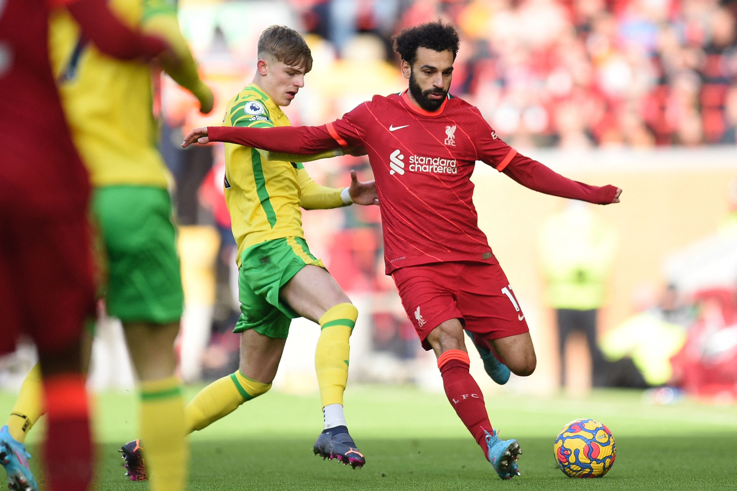 Bek Norwich City Brandon Williams (kiri) mencoba mengadang pemain Liverpool Mohamed Salah dalam laga Liga Premier Inggris di Stadion Anfield, Sabtu, 19 Februari 2022.