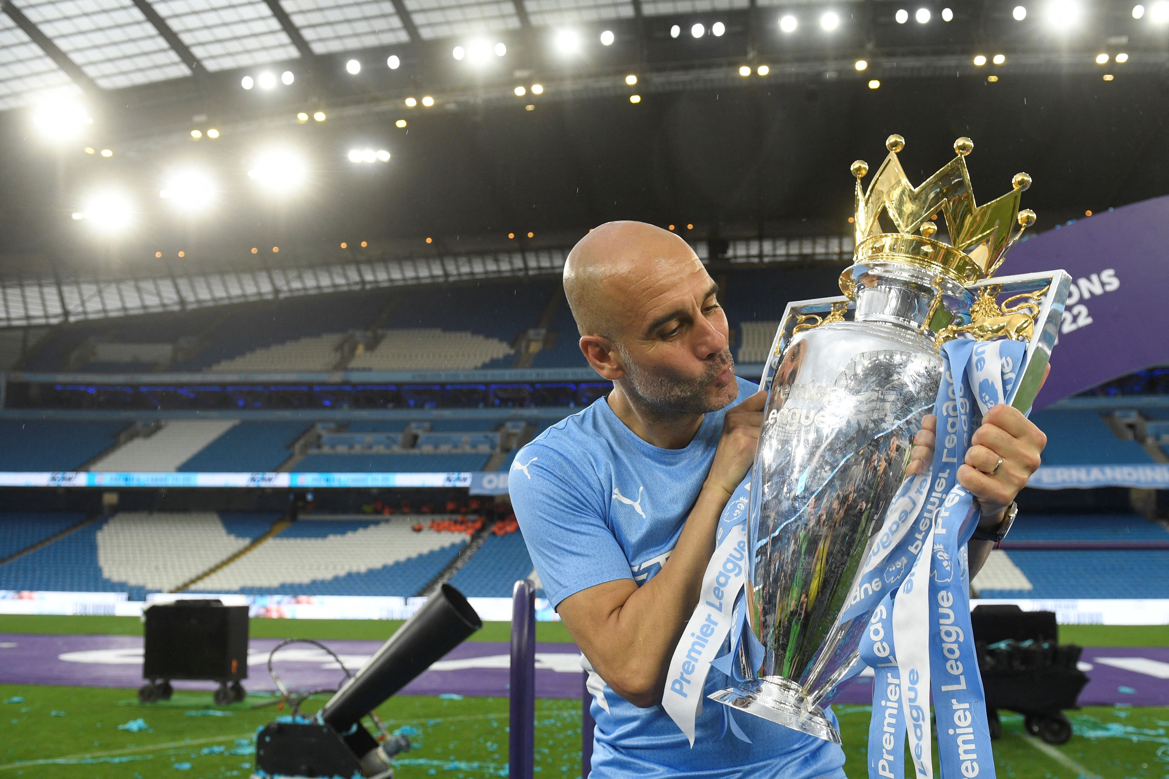 Pelatih Manchester City Pep Guardiola mencium trofi Liga Inggris.