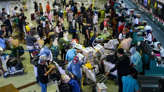 Calon penumpang pesawat terbang dengan bagasi mereka mengantre di loket check in Bandara Juanda, Surabaya.