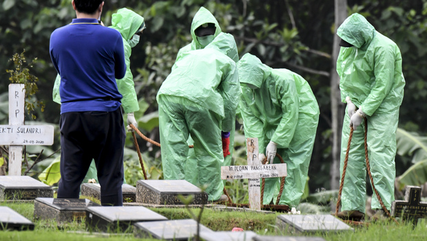 Petugas pemakaman menurunkan peti jenazah pasien Covid-19 di TPU Pondok Ranggon, Jakarta, Senin 30 Maret 2020. 