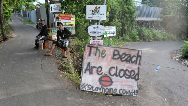 Pecalang atau petugas pengamanan adat Bali berjaga di sekitar kawasan wisata Pantai Balangan yang ditutup sementara selama pandemi Covid-19 di Badung, Bali, Minggu 29 Maret 2020.