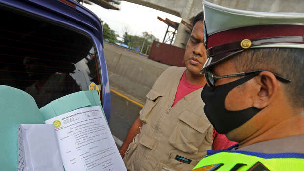 Petugas mengecek kelengkapan penumpang dalam kendaraan saat melintasi pos pemeriksaan PSBB di kawasan gerbang tol Cikarang, Bekasi, Jawa Barat, Kamis, 21 Mei 2020.