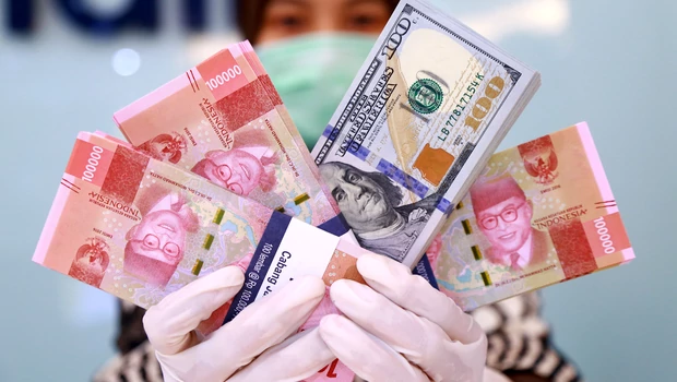 Karyawan memperlihatkan uang dolar AS diantara uang rupiah di sebuah bank di Jakarta.