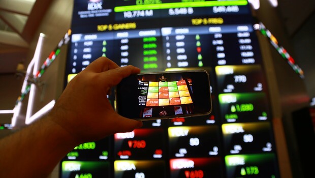 Investor memotret menggunakan telepon genggam pergerakan harga saham di Bursa Efek Indonesia (BEI), Jakarta.