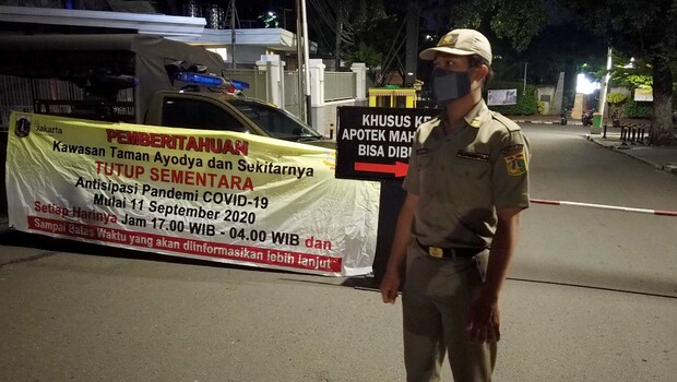 Petugas Satpol PP berjaga menutup jalan menuju Taman Ayodya di kawasan Bulungan, Blok M, Jakarta Selatan, Selasa, 22 September 2020 malam.