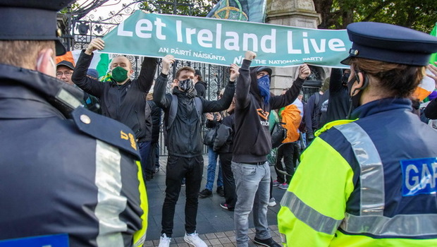 Para demonstran memegang spanduk saat protes terhadap pemerintah Irlandia yang memberlakukan pembatasan yang diberlakukan untuk membendung peningkatan jumlah kasus Covid-19, di luar Leinster House di Dublin, Sabtu (10/10/2020).