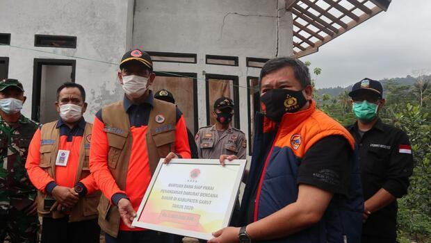 Kepala Badan Penanggulangan Bencana Nasional (BNPB) Letjen Doni Monardo (kiri) secara simbolis menyerahkan bantuan dana siap pakai untuk penanggulangan bencana banjir di Garut, Jawa Barat, Kamis, 15 Oktober 2020.