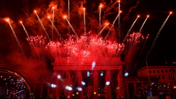Para seniman menyaksikan kembang api meledak di atas Gerbang Brandenburg yang terkenal di Berlin, Jerman untuk mengantar tahun baru saat konser 'Willkommen 2021' pada 1 Januari 2021. 