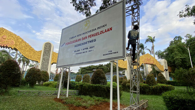 Pekerja menyelesaikan pemasangan papan pengumuman tentang pengambilalihan pengelolaan Taman Mini Indonesia Indah (TMII) di depan pintu masuk TMII, Jakarta Timur, Rabu, 7 April 2021.