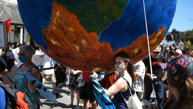 Aktivis lingkungan Extinction Rebellion membawa bola dunia raksasa saat menggelar aksi protes di jalan-jalan Falmouth, Cornwall, Inggris saat KTT G-7 pada Sabtu 12 Juni 2021.