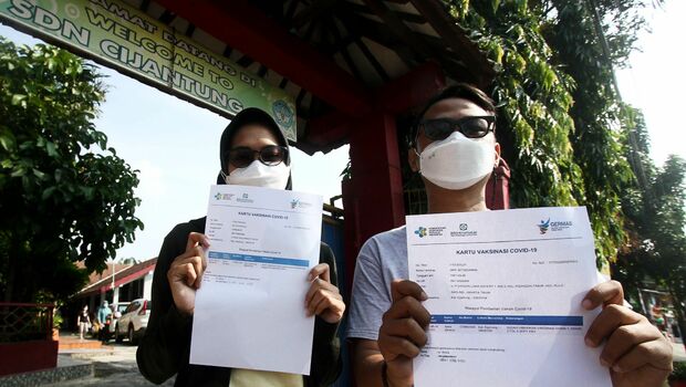 Warga menunjukan kertas sertifikat usai di vaksin Covid-19, di SD Negeri 01 Cijantung, Jakarta Timur, Senin 14 Juni 2021. BeritaSatuPhoto/Joanito De Saojoao.