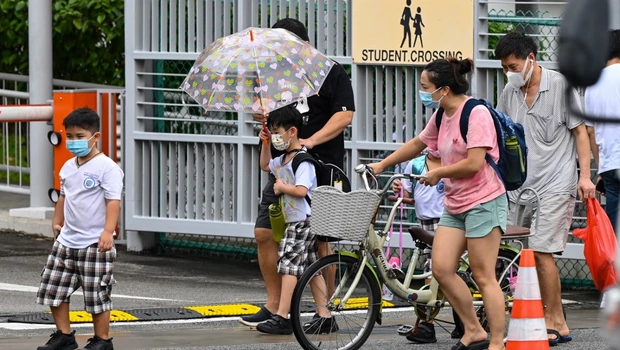 Anak-anak berjalan pulang dengan orang tua sepulang sekolah di Singapura pada 17 Mei 2021, saat Covid-19 menyebar.