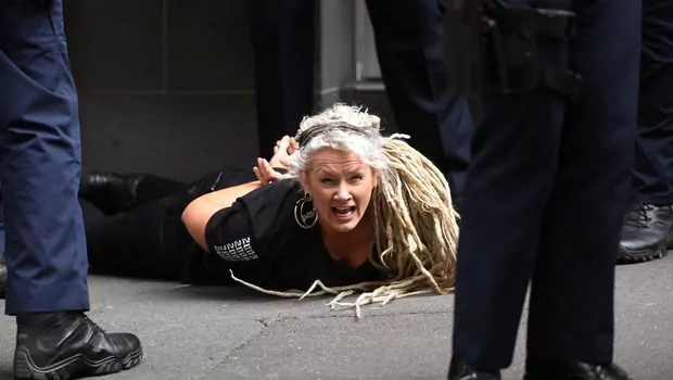Seorang demonstran terbaring dengan tangan terikat dan dikawal polisi dalam aksi protes menentang lockdown di Melbourne, Australia, 21 Agustus 2021. 