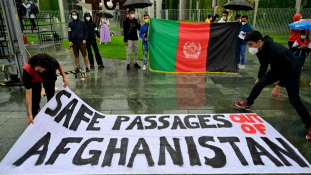 Para pengunjuk rasa mengibarkan bendera Afghanistan dan memegang spanduk yang mengklaim 