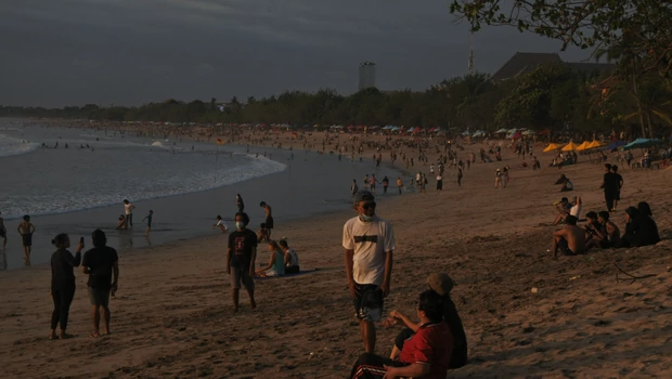 Wisatawan yang kebanyakan turis domestik menikmati suasana pantai Kuta, Bali, Minggu 24 Oktober 2021.