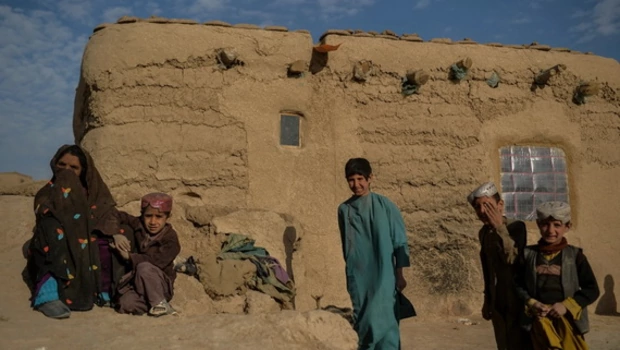 Satu keluarga Afghanistan berdiri di dekat rumah bata lumpur mereka di desa Haji Rashid Khan di distrik Bala Murghab. Gaya hidup Afghanistan menghasilkan 0,2 ton emisi CO2 per tahun, dibandingkan dengan 15 dari rata-rata orang Amerika, menurut data Bank Dunia. 