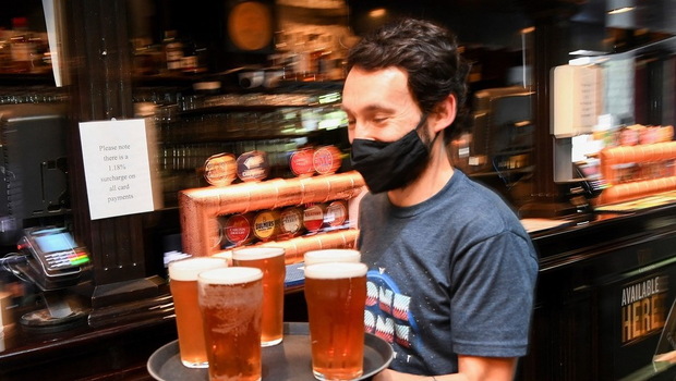 Seorang pelanggan membawa nampan bir ke mejanya di satu pub pusat kota Melbourne, Australia 22 Oktober 2021. 