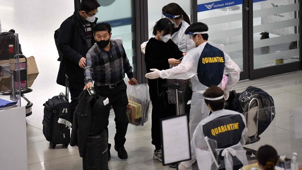 Petugas mengenakan APD memandu penumpang pesawat di aula kedatangan Bandara Internasional Incheon, Korsel, pada 30 November 2021, di tengah meningkatnya kekhawatiran tentang varian Omicron Covid-19.