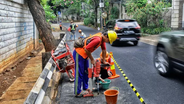 Pekerja mengebor aspal yang menutup sumur resapan di Jalan Lebak Bulus III, Cilandak, Jakarta Selatan, Senin, 6 Desember 2021.