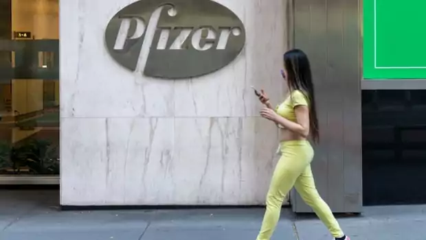 Seorang wanita berjalan di dekat kantor pusat Pfizer di New York City, Amerika Serikat. Perusahaan farmasi mengumumkan hasil awal yang positif pada uji coba vaksin Covid-19.