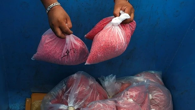 Petugas Badan Pengawasan Narkotika Thailand memasukkan kantong pil metamfetamin ke tong sampah pada saat upacara Penghancuran Narkotika Sitaan ke-50 di provinsi Ayutthaya, Thailand.
