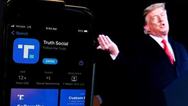 Ilustrasi foto ini menunjukkan gambar mantan presiden Donald Trump di sebelah layar ponsel yang menampilkan aplikasi Truth Social, di Washington, DC, pada Senin 21 Februari 2022.