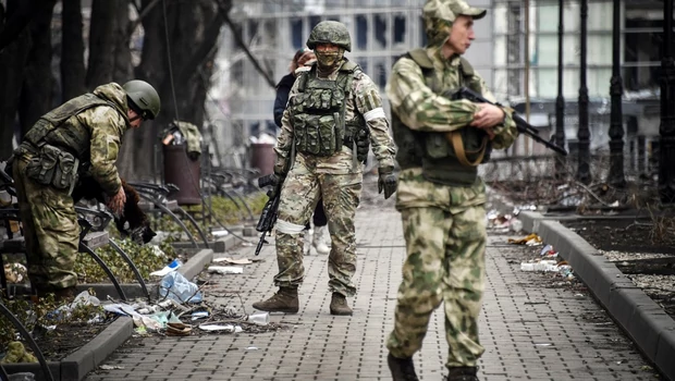 Tentara Rusia berjalan di sepanjang jalan di Mariupol pada 12 April 2022.