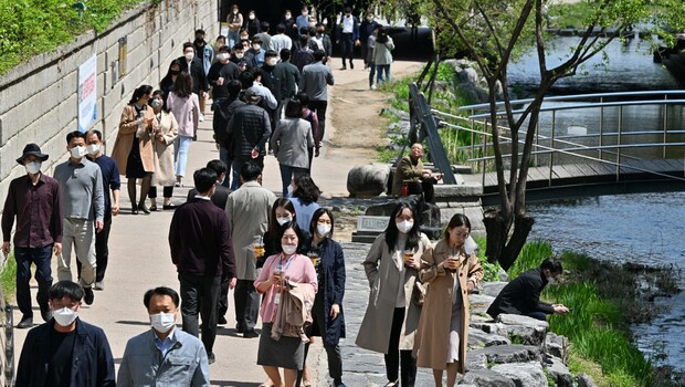 Orang-orang berjalan dengan mengenakan masker di sepanjang sungai Cheonggye di Seoul, Korea Selatan pada 15 April 2022.