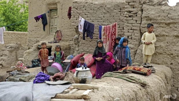 Anak-anak yang terkena banjir bandang duduk di luar rumah mereka yang rusak di distrik Qadis, provinsi Badghis, Afghanistan, pada Rabu 4 Mei 2022.