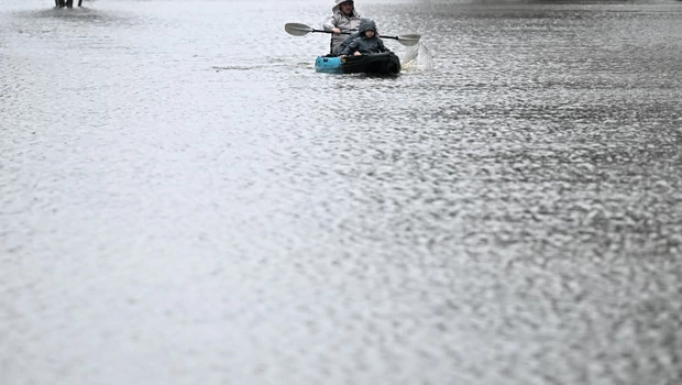 Seorang warga menggunakan kayak di sepanjang jalan yang banjir dari sungai Hawkesbury yang meluap akibat hujan deras di pinggiran Windsor Sydney pada 4 Juli 2022.