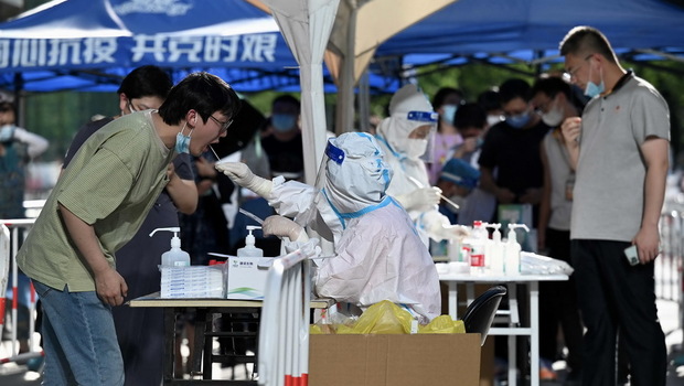 Seorang petugas kesehatan mengambil sampel swab dari seorang pria untuk diuji virus corona Covid-19 di tempat pengambilan swab di Beijing, Tiongkok pada Kamis 7 Juli 2022. 