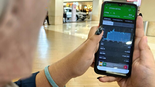 Investor memantau harga saham menggunakan ponsel di Jakarta.
