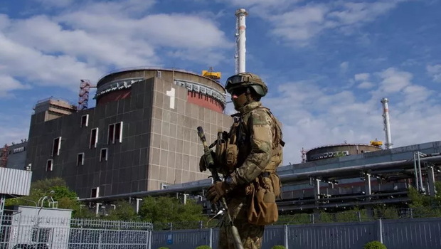 Seorang prajurit Rusia berpatroli di sekitar pabrik di Enerhodar, Ukraina, pada 1 Mei 2022. Ukraina menyatakan bahwa serangan Rusia terhadap pembangkit listrik tenaga nuklir Zaporizhzhia bisa disamakan dengan 