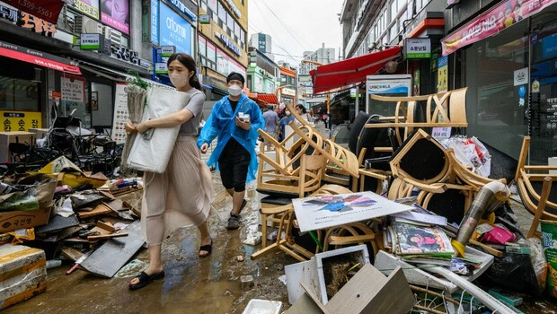 Pejalan kaki berjalan melewati puing-puing di luar toko-toko di Pasar Namseong di distrik Gangnam Seoul pada 9 Agustus 2022, setelah hujan yang menyebabkan banjir parah.