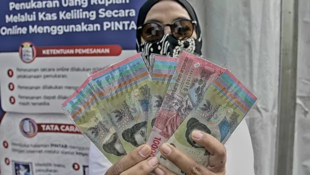 Warga menunjukan uang Rupiah kertas Tahun Emisi 2022 usai ditukarkan dengan uang lama, di Gelora Bung Karno (GBK) Hall Basket, Jakarta, Minggu 21 Agustus 2022.
