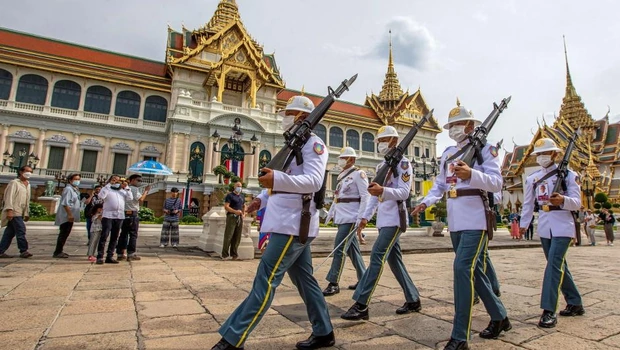 Turis menyaksikan penjaga berpatroli di tempat pemandangan Grand Palace di Bangkok, Thailand, pada 31 Juli 2022.
