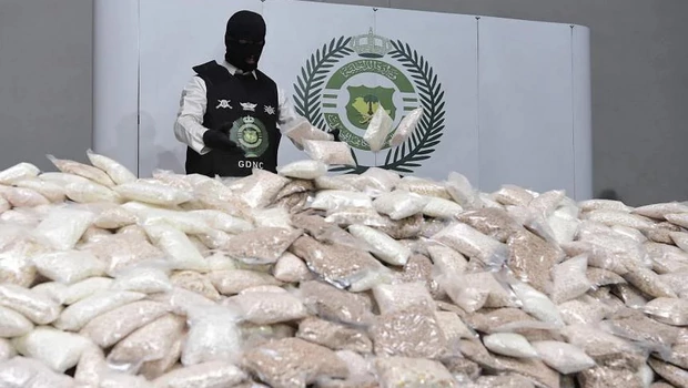 Seorang petugas keamanan Arabb Saudi menumpuk kantong pil amfetamin di satu gudang di lokasi yang dirahasiakan pada 31 Agustus 2022. 