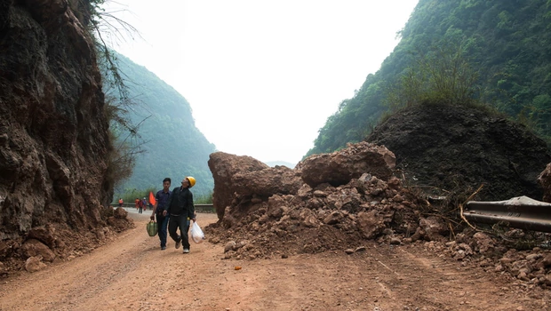 Warga berjalan pulang di jalan yang penuh dengan batu yang jatuh di daerah yang dilanda bencana di Ya'an, provinsi Sichuan, Tiongkok barat daya pada 21 April 2013. Jalan yang tersumbat, puing-puing, dan tanah longsor menghambat penyelamatan.