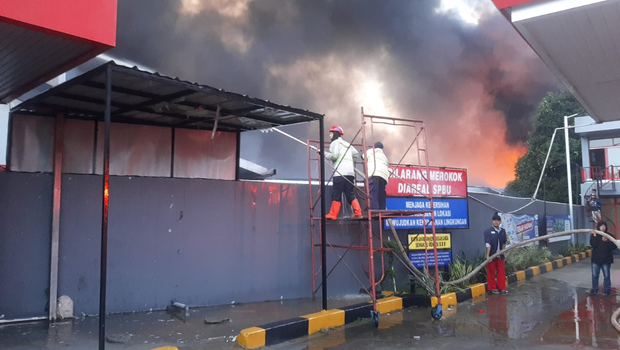 Petugas pemadam kebakaran berupaya memadamkan kebakaran yang melanda gudang jasa pengiriman barang milik JNE di kawasan Jalan Pekapuran, Cimanggis, Depok terbakar Senin, 12 September 2022 dini hari.