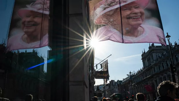 Warga berjalan di bawah gambar mendiang Ratu Elizabeth II yang tergantung di luar sebuah toko di Jalan Piccadilly, London, 17 September 2022.