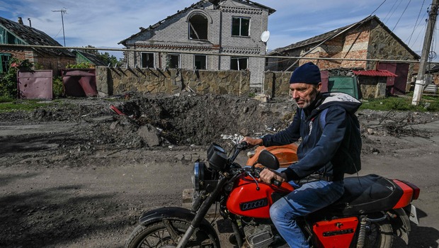 Seorang pria mengendarai sepeda motor melewati reruntuhan bangunan yang hancur dalam invasi militer Rusia di Siversk, wilayah Donetsk di timur Ukraina pada 20 September 2022.