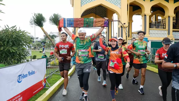 Gubernur Jawa Tengah Ganjar Pranowo tampak sumringah sambil mengangkat kain tenun Ulos saat tiba di garis finish Bank Jateng Friendship Run Borobudur Marathon 2022 di Medan, Sumatera Utara, pada Minggu, 25 September 2022.