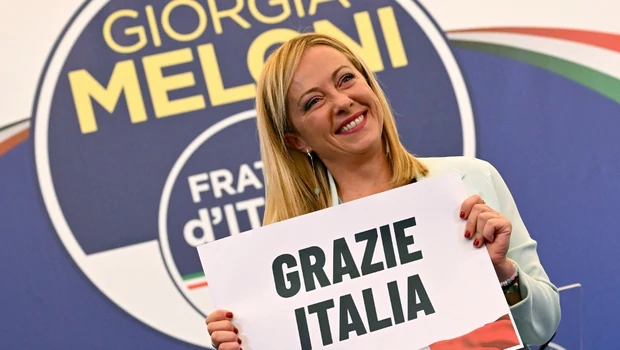 Pemimpin sayap kanan Italia dari partai Brothers of Italy, Giorgia Meloni memegang plakat bertuliskan 