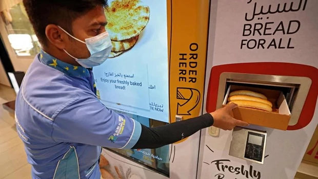 Seorang pria mengumpulkan roti dari mesin penjual otomatis di Dubai, Uni Emirat Arab pada Kamis 22 September 2022. 