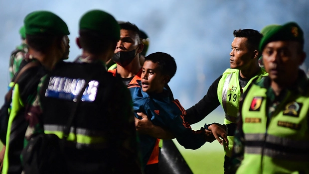 Anggota TNI mengamankan seorang anak dalam pertandingan sepak bola antara Arema FC dan Persebaya Surabaya di stadion Kanjuruhan di Malang, Jawa Timur, Sabtu, 1 Oktober 2022.