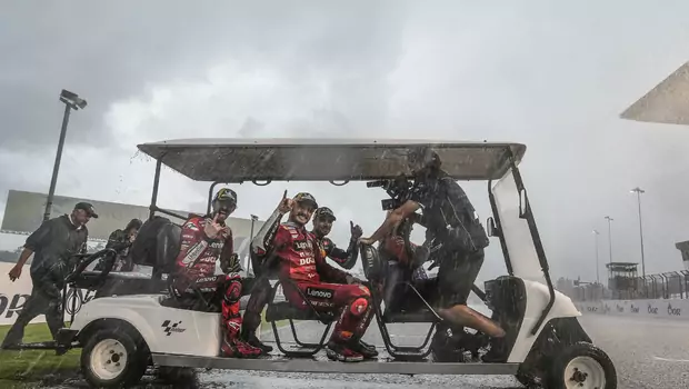 Fransesco Bagnaia, Jack Miller, dan Miguel Oliveira naik mobil golf di tengah hujan deras menuju podium setelah Grand Prix Thailand, 2 Oktober 2022.